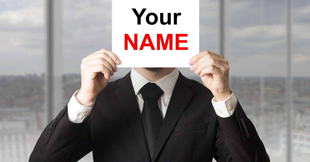 A man holding "Your Name" card up with two hands
